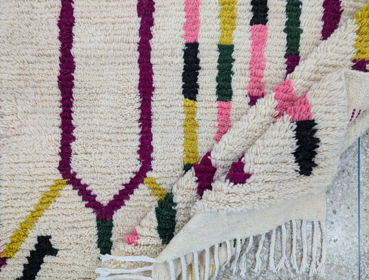 Tapis Beni Ouarain légèrement plié, montrant la souplesse de la laine et la qualité du tissage fait main