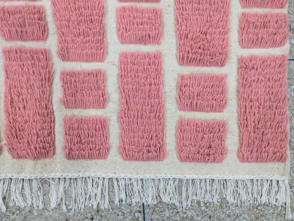 Franges nouées à la main d’un tapis berbère en laine rose marocain