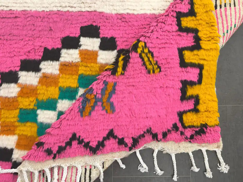 Tapis azilal coloré partiellement replié montrant l’envers solide et le tissage multicolore du dessus