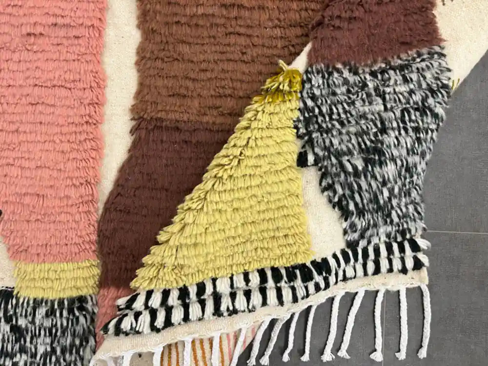 Tapis azilal multicolore plié montrant le dessous et la souplesse de la laine