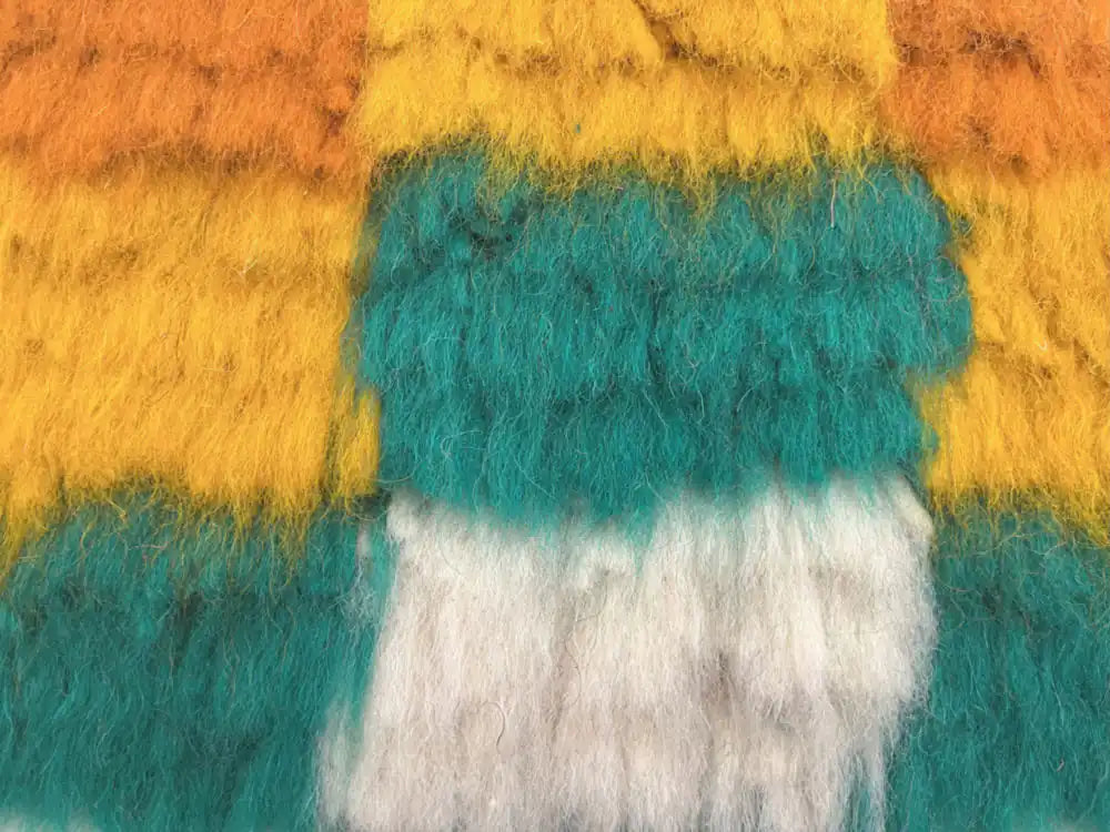 Zoom sur la laine épaisse et colorée jaune, verte et blanche du tapis azilal coloré marocain