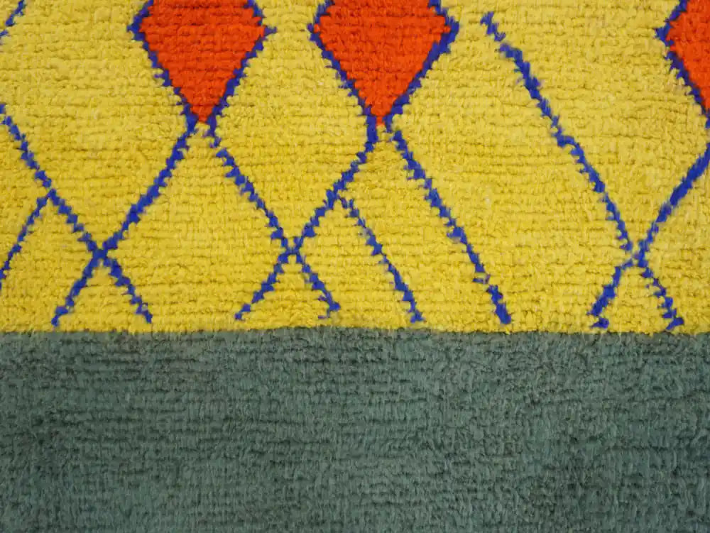 Détail du grand tapis Beni Ouarain, laine épaisse, losanges berbères rouges et lignes bleues sur jaune