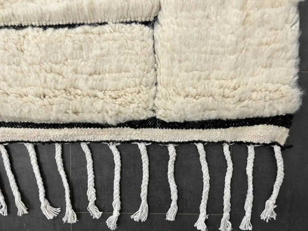 Finition franges du tapis berbère Beni Ouarain, laine 100% naturelle, design noir et blanc élégant.