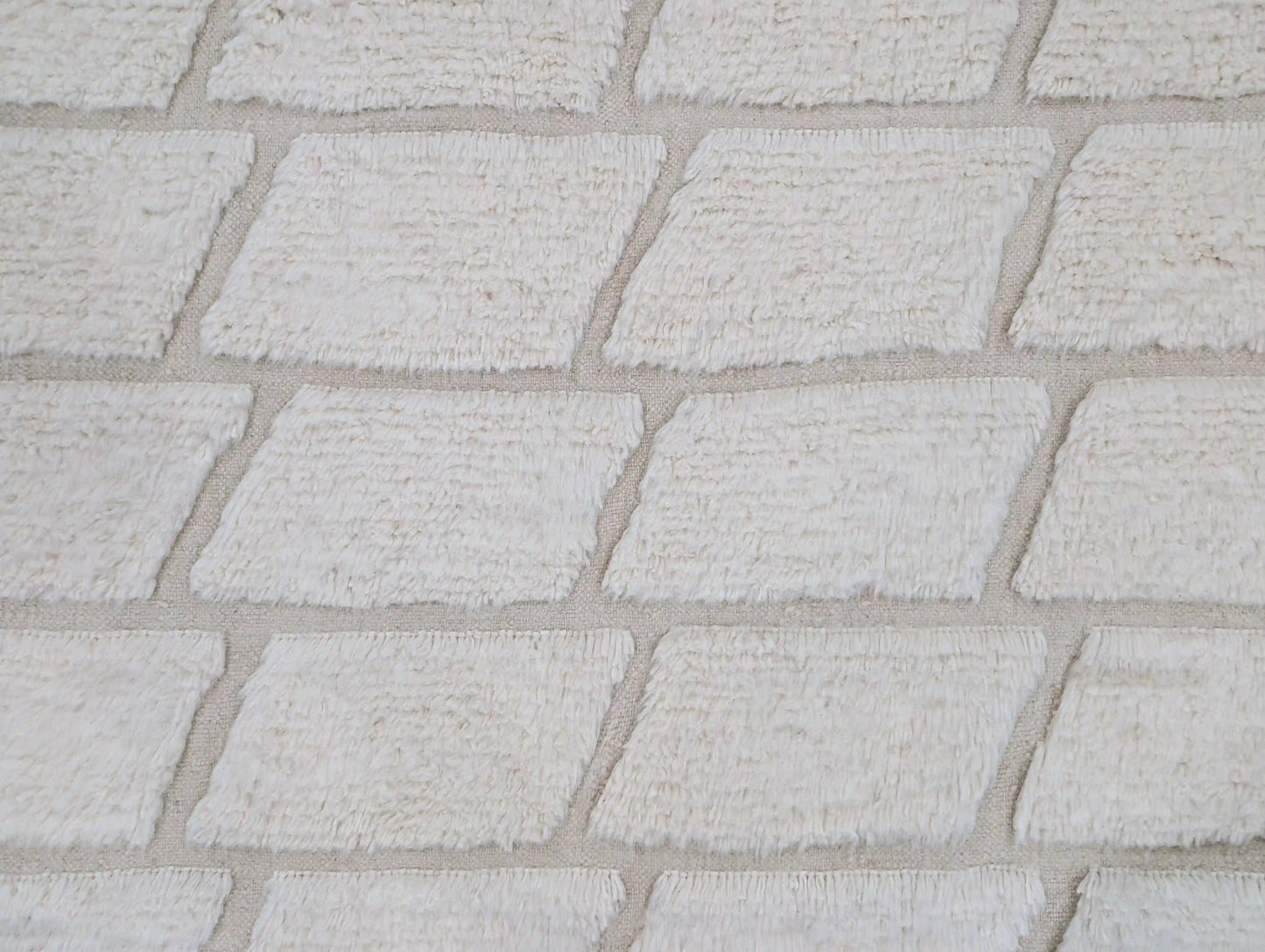 Gros plan sur les motifs géométriques d’un tapis Beni Ouarain blanc en laine épaisse