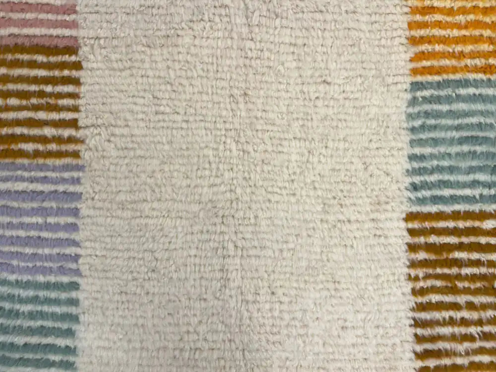 Gros plan sur un tapis berbère azilal blanc à motifs colorés, texture moelleuse et laine épaisse