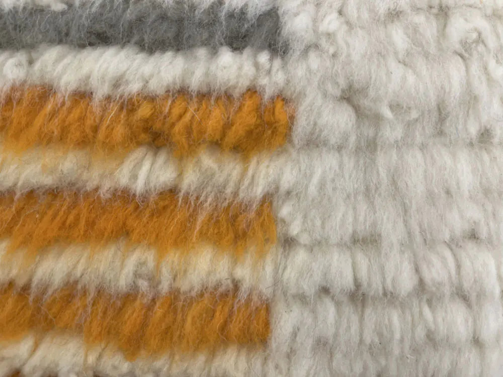 Détail laineux d’un tapis berbère azilal à rayures orange et blanches, style marocain traditionnel