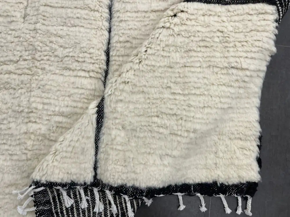 Envers du tapis Beni Ouarain, tissage traditionnel marocain en laine, motifs noirs sur fond blanc.