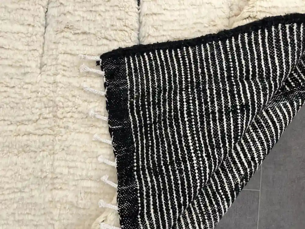 Vue du dos du tapis Beni Ouarain berbère, rayures noires et blanches, artisanat marocain authentique.