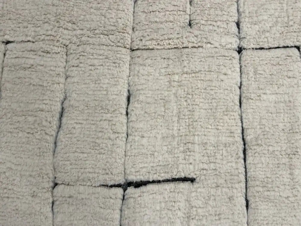 Détail du tapis berbère Beni Ouarain en laine naturelle, motifs noirs sur fond blanc, fait main au Maroc.