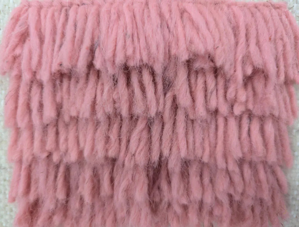 Gros plan sur la texture épaisse et naturelle d’un tapis berbère en laine