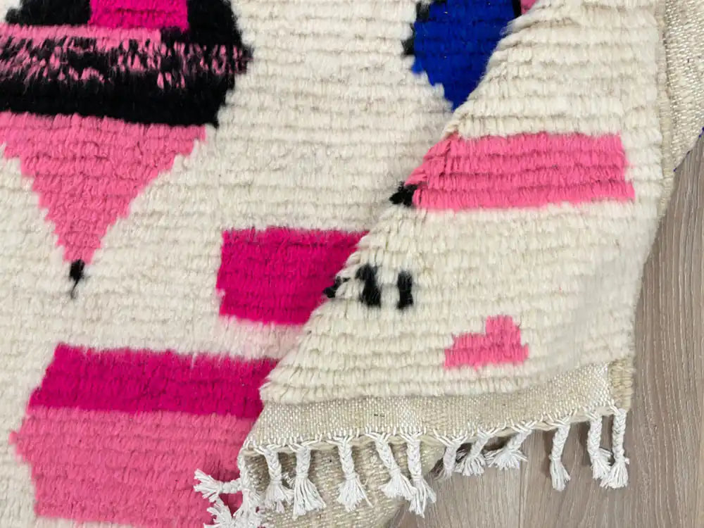 Tapis Azilal plié révélant la texture de la laine et la finition des franges.