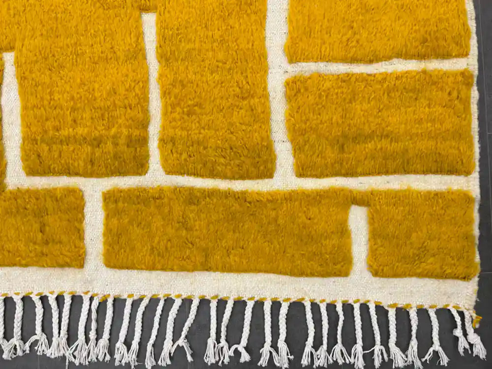 Franges artisanales du tapis Beni Ouarain jaune moutarde, finition traditionnelle marocaine.