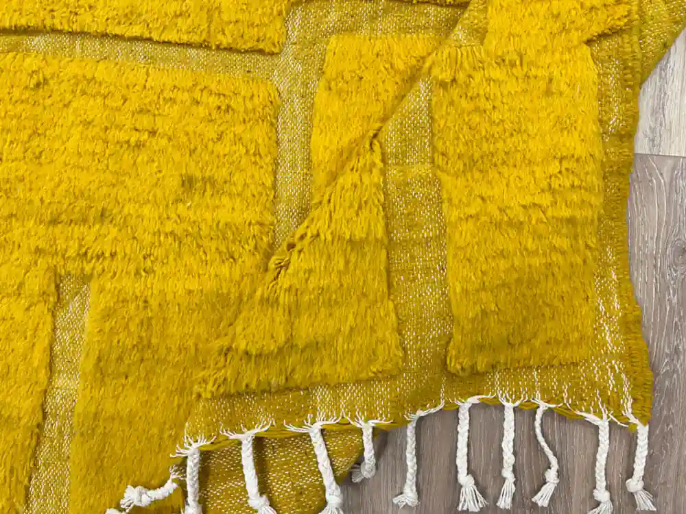 Tapis Beni Ouarain plié avec vue sur la frange et la texture de la laine naturelle.