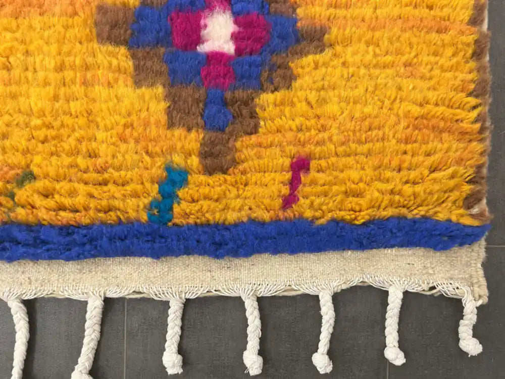Franges et bordure jaune à motifs géométriques d’un tapis Azilal traditionnel