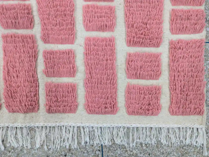 Franges nouées à la main d’un tapis berbère en laine rose marocain