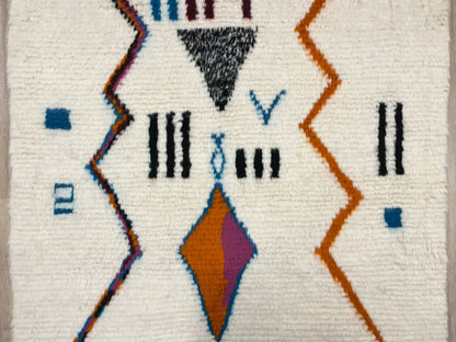 Zoom sur le centre du tapis berbère montrant les lignes géométriques abstraites en laine naturelle.