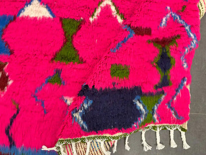 Tapis boujaad coloré partiellement replié montrant l’envers solide et le tissage multicolore du dessus