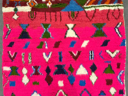 Motif multicolore sur fond rose vif d’un tapis boujaad tissé main, détails précis
