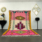 Grand tapis azilal coloré avec motifs géométriques et fond rose, exposé dans un salon moderne marocain