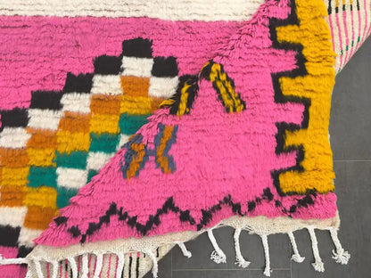 Tapis azilal coloré partiellement replié montrant l’envers solide et le tissage multicolore du dessus