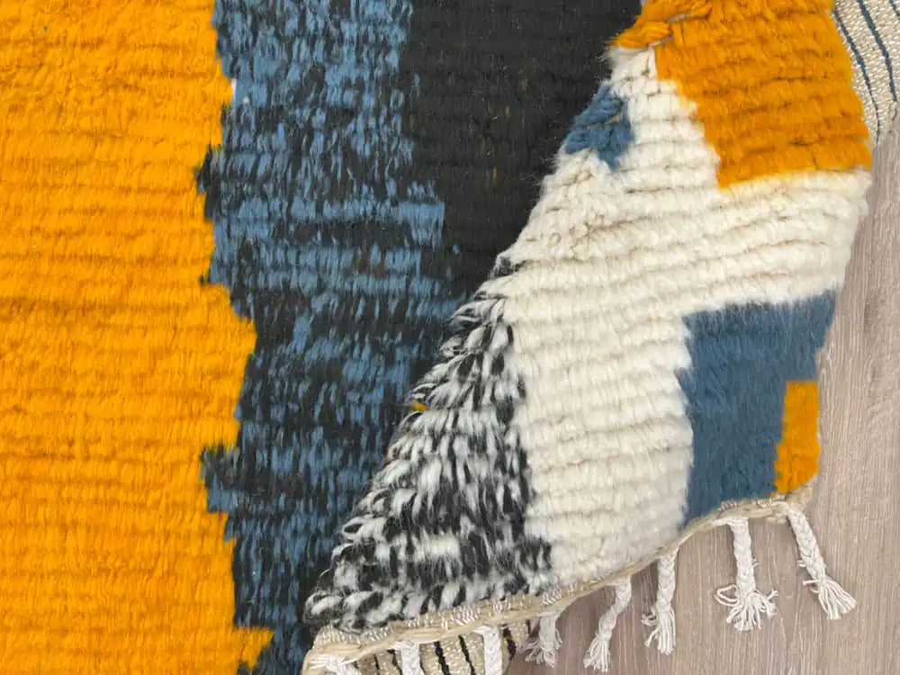 Tapis Azilal plié montrant la texture de la laine et les franges tissées à la main