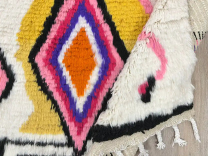 Tapis Azilal plié, avec un aperçu de la frange et de la matière en laine naturelle, illustrant sa qualité et sa texture.