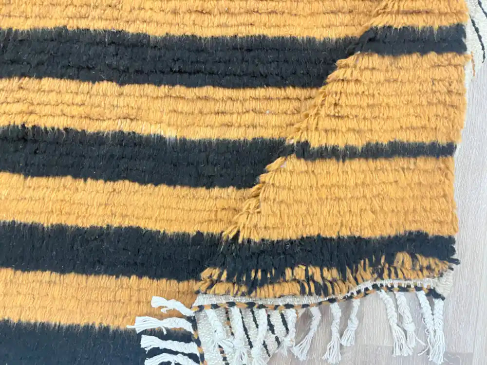 Pli d’un tapis Beni Ouarain à motif orange et noir en laine naturelle