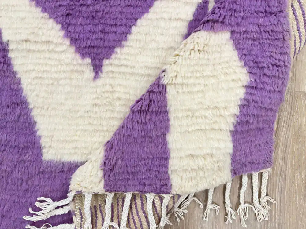 Tapis berbère Beni Ouarain plié montrant la laine naturelle épaisse et les franges artisanales.