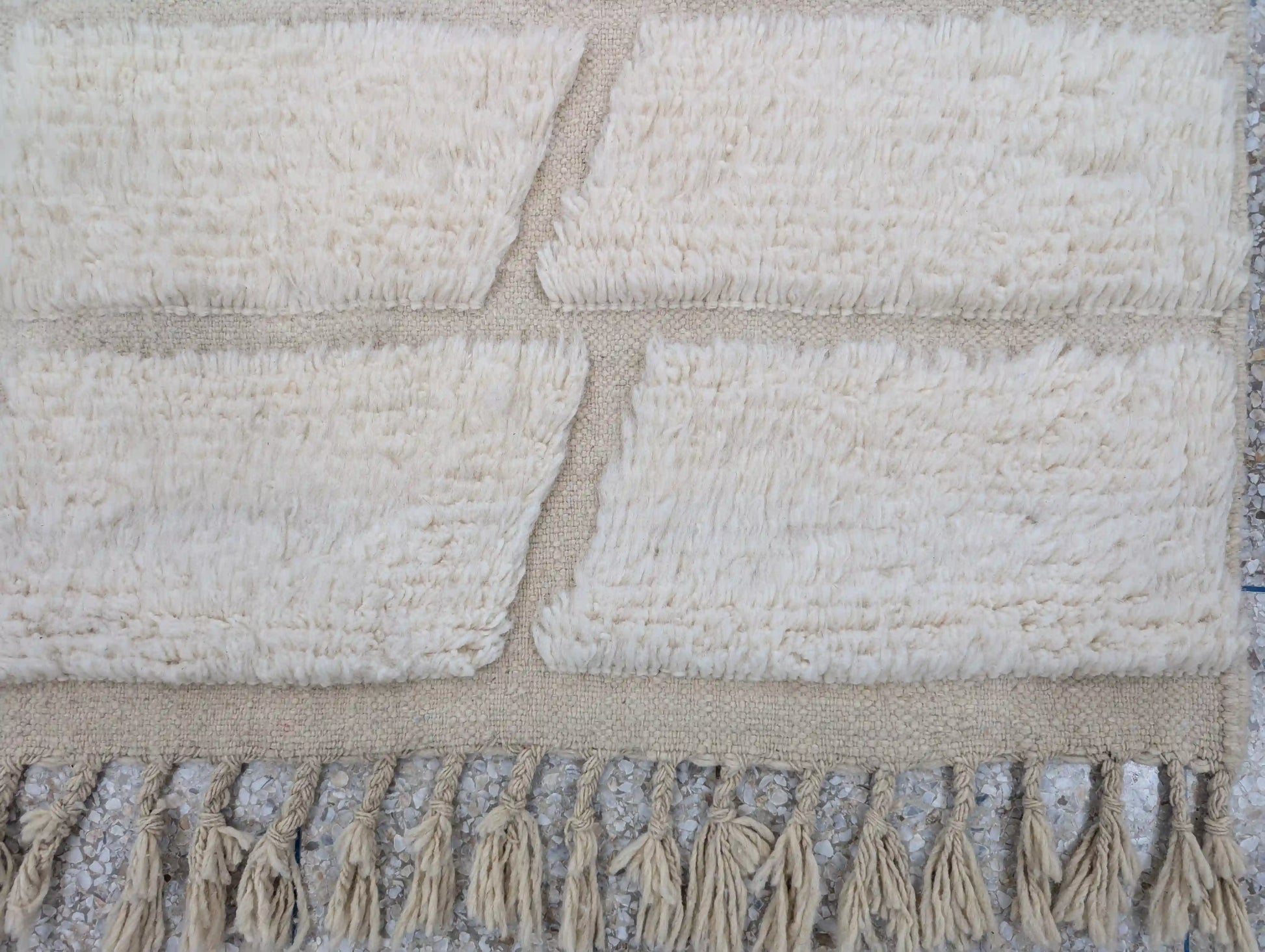 Détail des franges d’un tapis Beni Ouarain blanc fait main, finition artisanale traditionnelle