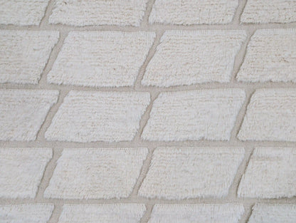 Gros plan sur les motifs géométriques d’un tapis Beni Ouarain blanc en laine épaisse