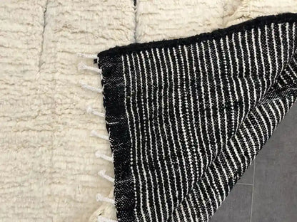Vue du dos du tapis Beni Ouarain berbère, rayures noires et blanches, artisanat marocain authentique.
