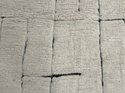 Détail du tapis berbère Beni Ouarain en laine naturelle, motifs noirs sur fond blanc, fait main au Maroc.