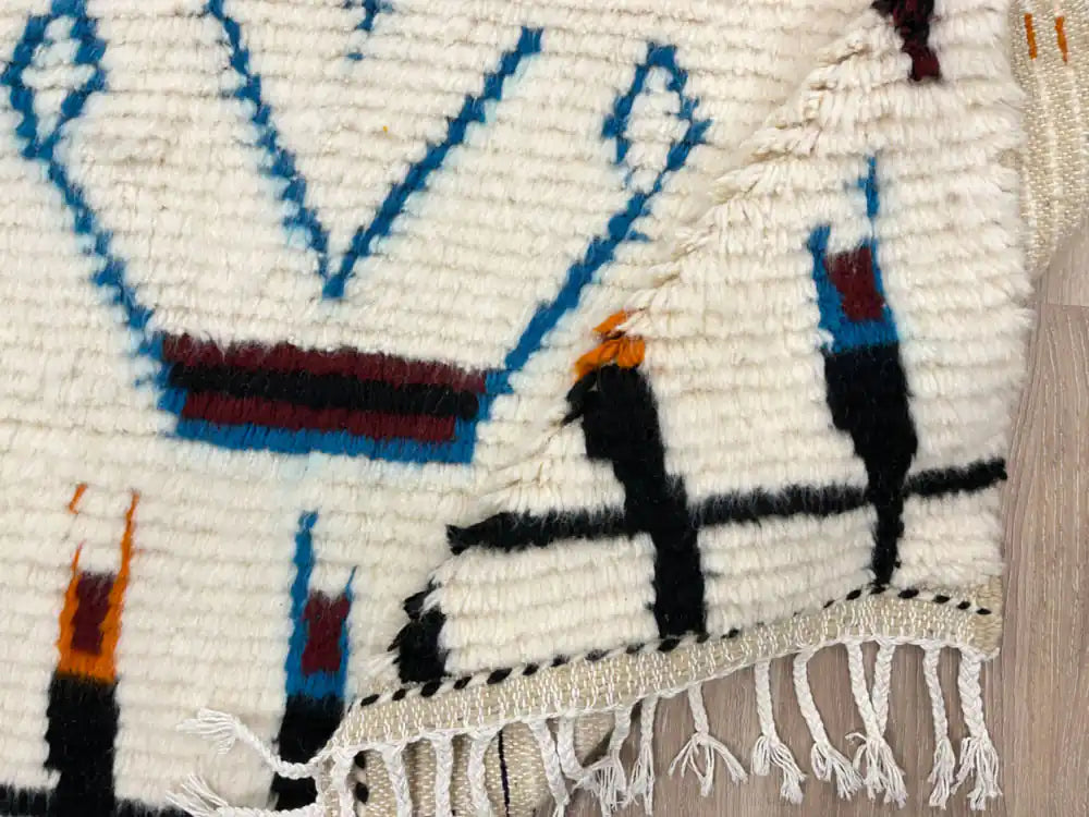 Tapis berbère moderne plié avec vue sur la frange et la qualité de la laine naturelle.