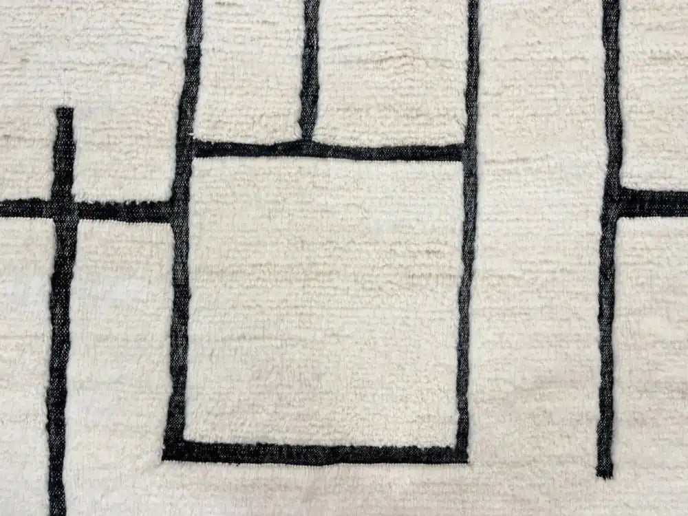 Tapis Blanc Beni Ouarain en laine naturelle avec motifs géométriques noirs, fait main au Maroc, parfait pour salon moderne.