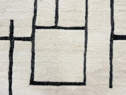 Tapis Blanc Beni Ouarain en laine naturelle avec motifs géométriques noirs, fait main au Maroc, parfait pour salon moderne.