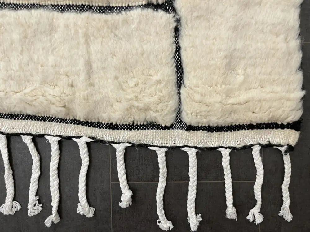 Franges du tapis Blanc Beni Ouarain nouées à la main, authenticité et finition haut de gamme pour décoration chic.