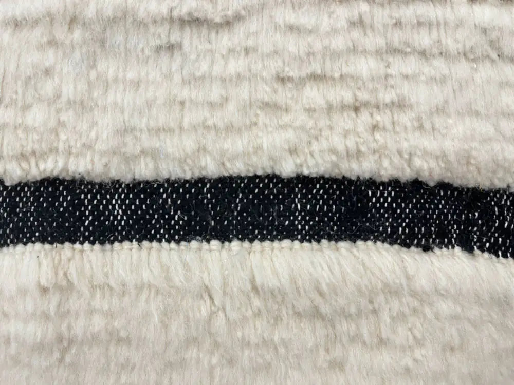 Gros plan sur la laine douce d’un tapis Blanc Beni Ouarain, qualité artisanale berbère, idéal pour intérieur chaleureux.