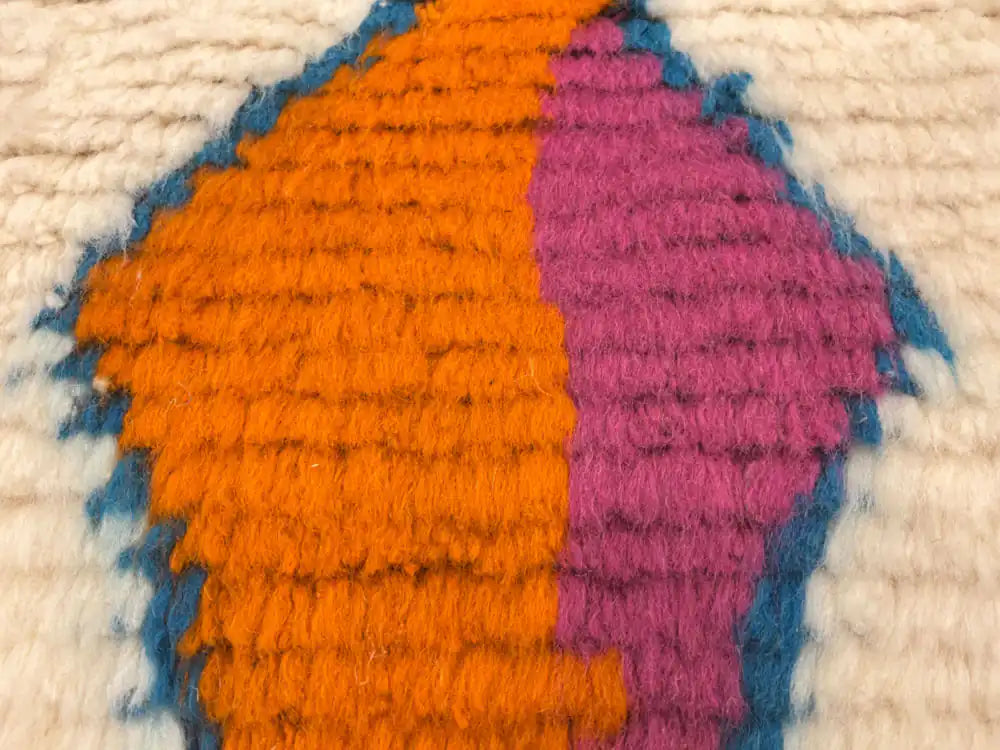 Gros plan sur la matière du tapis berbère en laine de mouton, texture épaisse et douce tissée à la main.